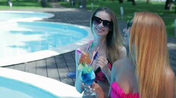 Two women drink cocktails on the swimming poolside video