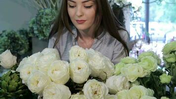 Female florist looks at white roses at flower shop video