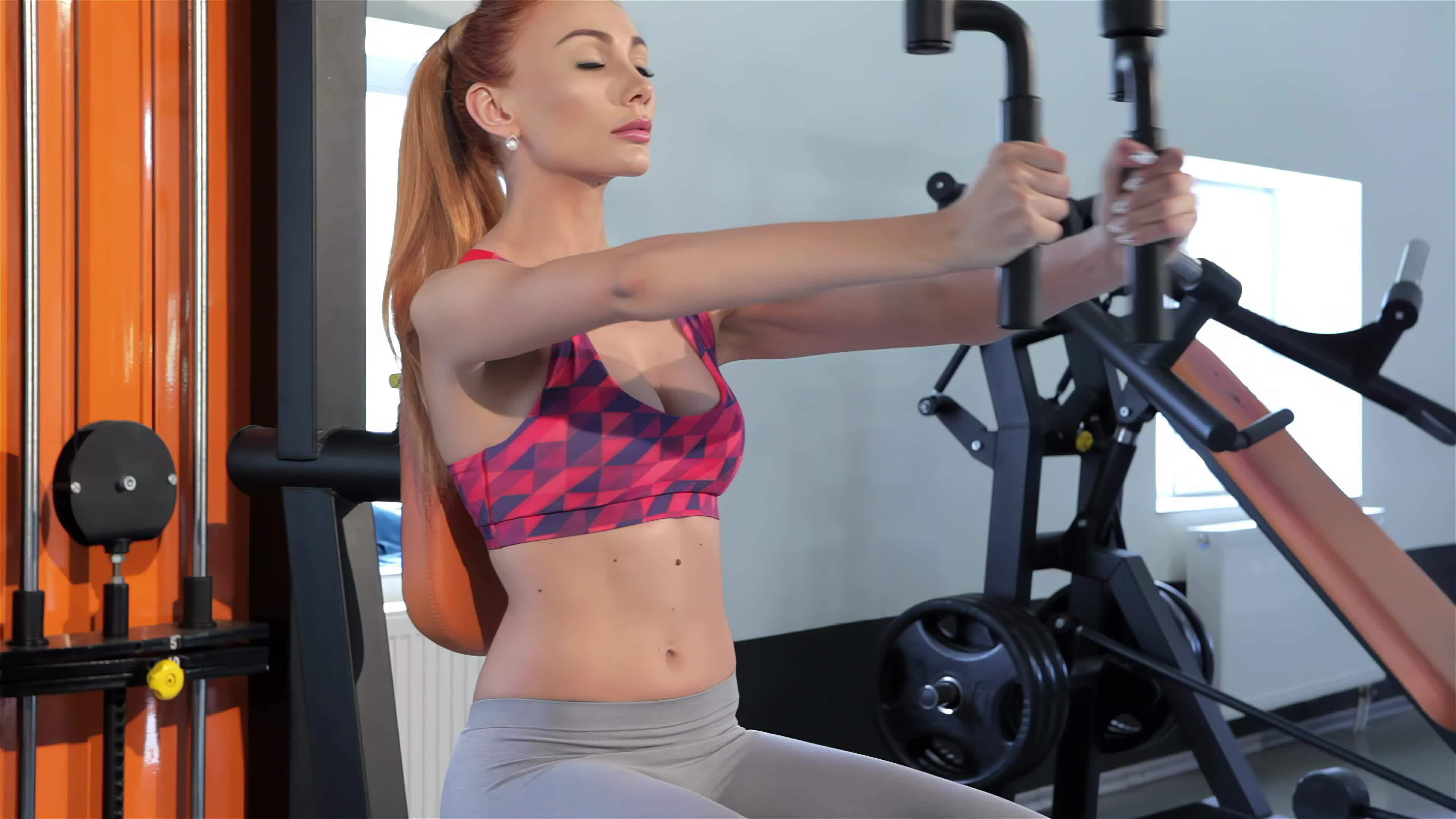 Woman trains her chest muscles on pec deck machine at the fitness