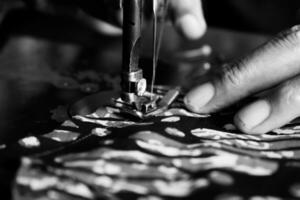 Vintage Black and White Close up Senior Female Tailor Sewing batik indonesian fabric into cloth, elder senior and vintage black and white concept photo