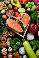 Heart health foods salmon, avocados, blueberries, broccoli, nuts and mushrooms. On a black stone background. Top view. Copy space. photo