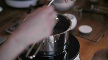 stirring wax with a wooden stick on a water bath, handmade candle making video