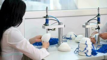 flickor arbete på de maskin för de tillverkning av medicinsk masker med nanofiber och löda de slingor till dem med ultraljud. coronovirus och covid-19 förebyggande video