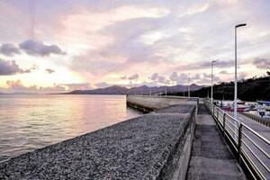 a sunset over the water with a pier and cars parked on it photo