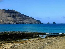 a beach with rocks and a mountain in the background photo