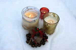 photo Burning candles in glass candlesticks and Christmas bells on the snow