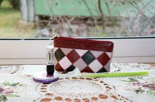 Cosmetic bag, powder, lipstick with an artificial calla flower on a table with a napkin near the window, horizontal photo