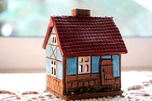 Ceramic candlestick in the shape of a house with a burning candle inside. Model of a house with burning windows, horizontal photo, close-up photo