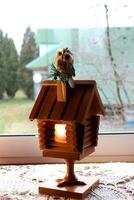 A wooden electric retro lamp in the form of a hut on chicken legs with a toy owl on a chimney, a fairy-tale house with a burning window. Vertical photo, close-up photo