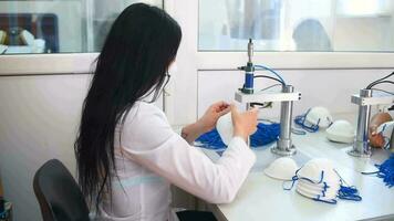 The girl works in a factory for the production of medical masks with nanofibre and solder loops with ultrasound on a machine. Coronavirus and Covid-19 Protection.Close-up. video