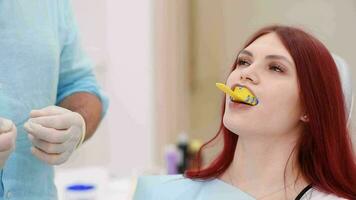 The orthodontist placed a spoon with silicone material in the patient's mouth to take an impression of her teeth video