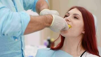 The orthodontist shows the patient an impression tray in which the silicone impression material will be placed to get the shape of her teeth video