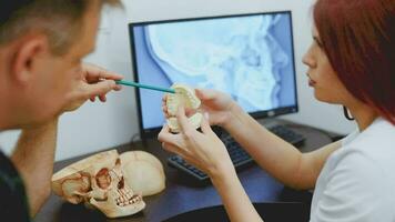 Doctor dentist teaches a student how to treat teeth using the example of a ceramic jaw video