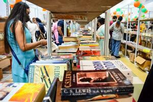 Delhi, India, septiembre 09 2023 - varios años grupo personas leyendo variedad de libros en estante dentro un puesto de libros a Delhi internacional libro justo, selección de libros en monitor en anual libro justa foto