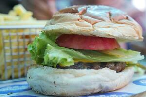 hamburguesa con queso con ensalada y tomate en un de madera tablero foto