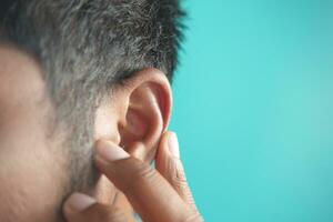 young man having ear pain touching his painful ear , photo