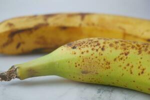 comparing rotten banana with a ripe banana on a white background photo