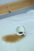 cup of coffee spilled on gray white bed photo