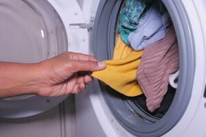 men hand putting a cloths in a washing machine. photo