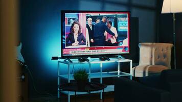 Close up shot of TV left open at night in cozy dimly lit apartment showing news channel. Home entertainment system showing broadcast of television reports in living room illuminated by blue light video