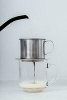 Coffee maker pouring coffee into a glass cup on white background photo
