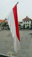 el indonesio rojo y blanco bandera revolotea en parte superior de el antiguo holandés patrimonio edificio. ver desde el ventana. foto