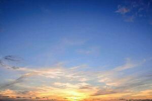 the sun sets over the ocean in a blue sky photo