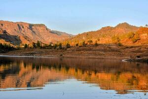 un lago rodeado por montañas y un azul cielo foto