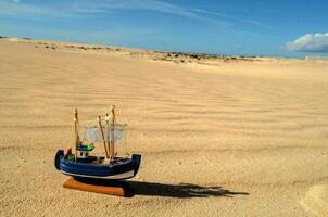 a small boat in the sand with a blue sky photo