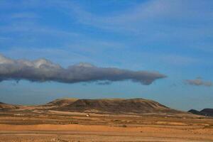 a desert with a few clouds in the sky photo