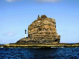 a lighthouse on a rock in the middle of the ocean photo