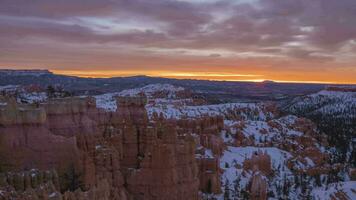 bryce kanjon huva på soluppgång i vinter. snö, molnig himmel. bryce kanjon nationell parkera. utah, usa. rörelse panorering tid upphöra video