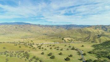 Train and Hilly Green Farmland. Kern County. California, USA. Aerial View. Drone Flies Forward video