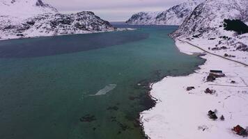 Straße, Fahnenpollen und Berge im Winter. wolkig Himmel. Flakstadoya, Lofoten Inseln, Norwegen. Antenne Sicht. Drohne fliegt nach vorne, Neigung hoch. verraten Schuss video