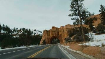 Car Driving on Road through Arch Tunnel on Winter Day. Red Canyon. Dixie National Forest. Utah, USA video