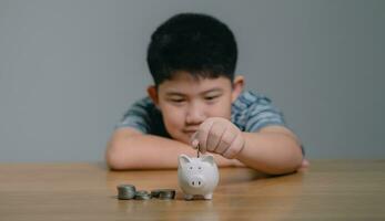 Asian boy saving money puts coins in piggy bank, Save money and finance concept, Saving money for the future photo