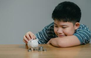 Asian boy saving money puts coins in piggy bank, Save money and finance concept, Saving money for the future photo
