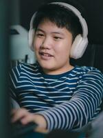 estilo de vida asiático pequeño Niños sonrisa utilizar escritorio piezas computadora a jugar profesional vídeo juegos con auriculares en el casa, charla con amigos, y entretenimiento foto