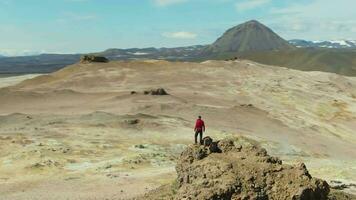 Man Traveler Stands on Mountain Top in Hverir Area. Icelandic Landscape. Iceland. Aerial View. Drone is Orbiting video