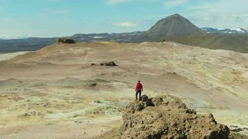 hombre viajero soportes en montaña parte superior en hverir área. islandés paisaje. Islandia. aéreo vista. zumbido es orbital video