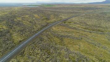 blanco coche en la carretera y volcánico lava rock formaciones en nublado día. Islandia. aéreo vista. zumbido moscas adelante video