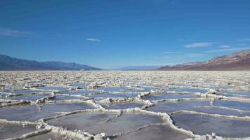 Badwater Basin at Sunny Day. Salt Crust Formations with Water and Blue Sky. Death Valley National Park. California, USA. Aerial View video