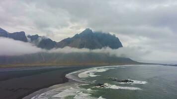 Vestrahorn berg en zee kust. zwart zand strand en golven. stokksnes schiereiland. IJsland. antenne hyper vervallen video