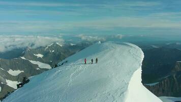 grupp av människor på topp av snötäckt berg i europeisk alps i solig morgon. antenn se. Drönare är kretsande video