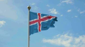 ondulación bandera de Islandia y azul cielo con nubes en antecedentes. lento movimiento video