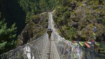 porter est en marchant sur suspension pont dans khumbu. l'Himalaya, Népal. lent mouvement video