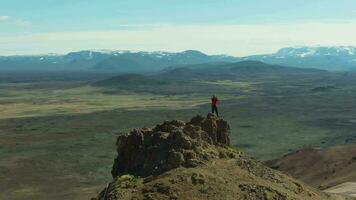 fotógrafo hombre viajero en montaña parte superior tomando imágenes en hverir zona en soleado día. Islandia. aéreo vista. zumbido es orbital video