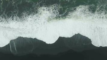 Ozean abstürzen Wellen. reynisfjara schwarz Sand Strand, Island. Antenne Vertikale von oben nach unten Sicht. Drohne fliegt seitwärts video