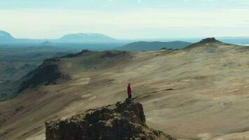 hombre viajero soportes en montaña parte superior en hverir zona en soleado día. Islandia. aéreo vista. zumbido es orbital video