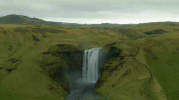 skogafoss vattenfall och grön landskap på molnig dag. island. antenn se. Drönare flugor bakåt och uppåt video